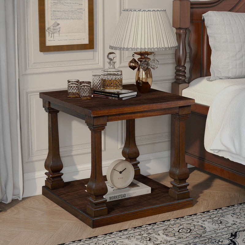Walnut-finish square side table with turned legs and a lower shelf beside a bed.