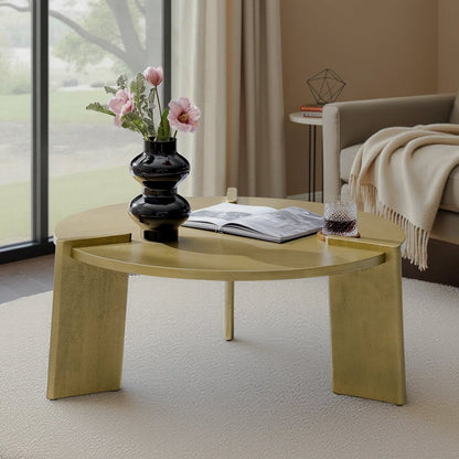 Golden round coffee table with three broad slab legs and raised edge details beside a sofa