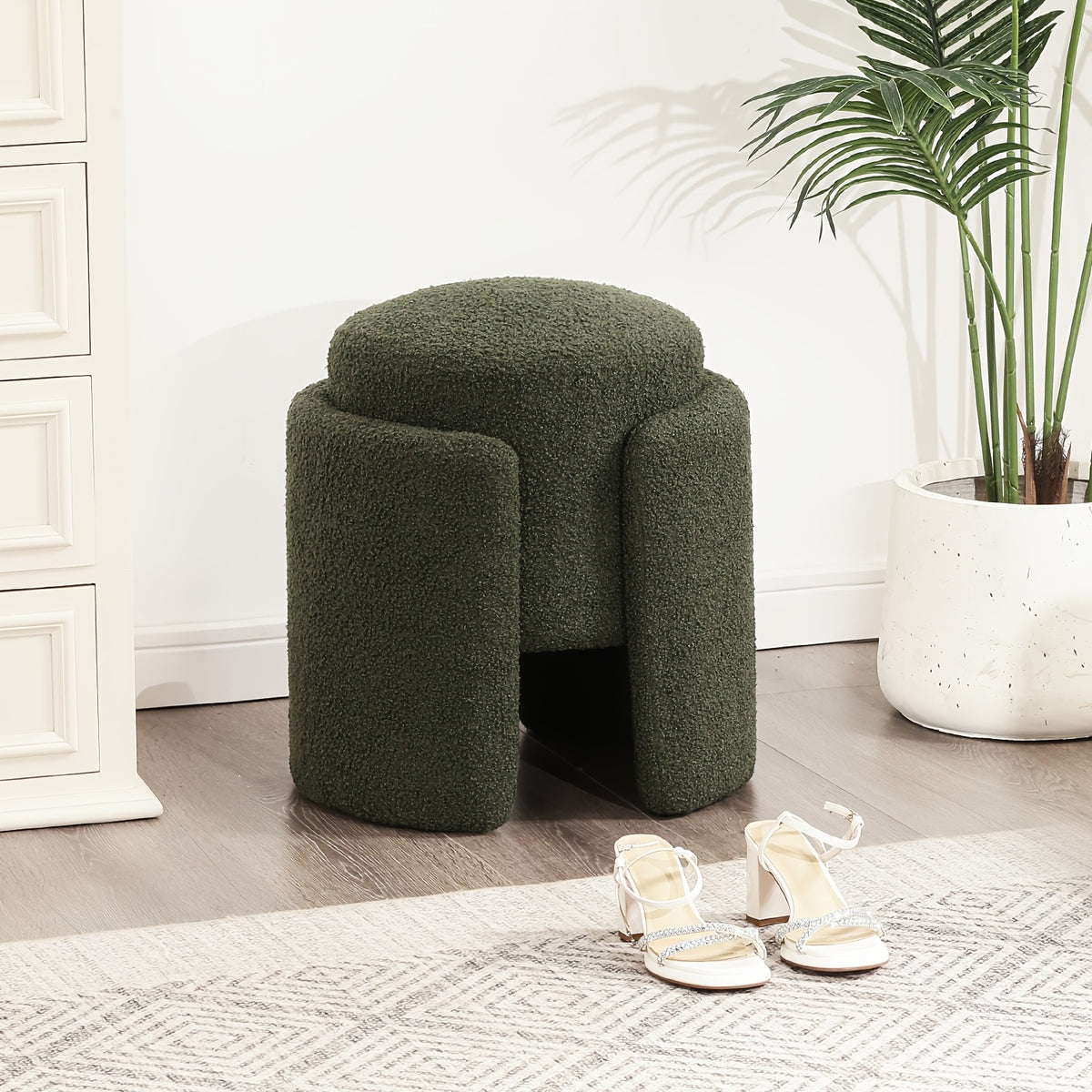 Green upholstered ottoman with split pedestal sides beside a bedroom
