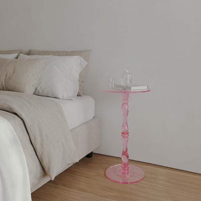 Pink acrylic pedestal table beside a bed