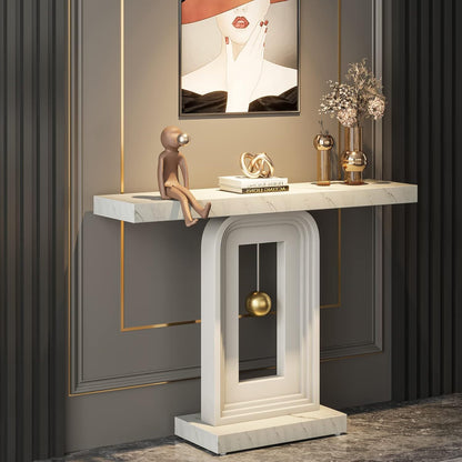 White marble-look console with arched pedestal and gold sphere against a dark paneled entryway wall