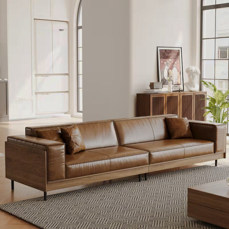 Front view of a long brown sofa with a wood surround and slim dark legs