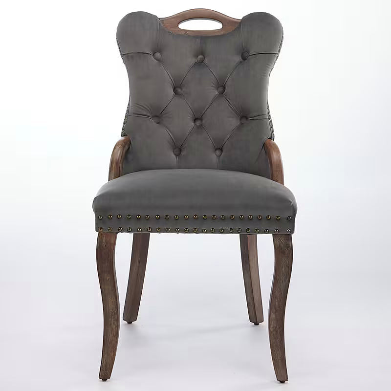 Gray velvet dining chair with a tufted back, wood handle, and curved wood legs