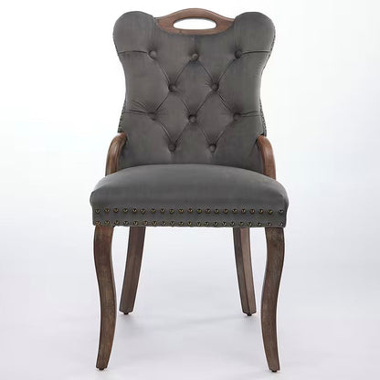 Gray velvet dining chair with a tufted back, wood handle, and curved wood legs