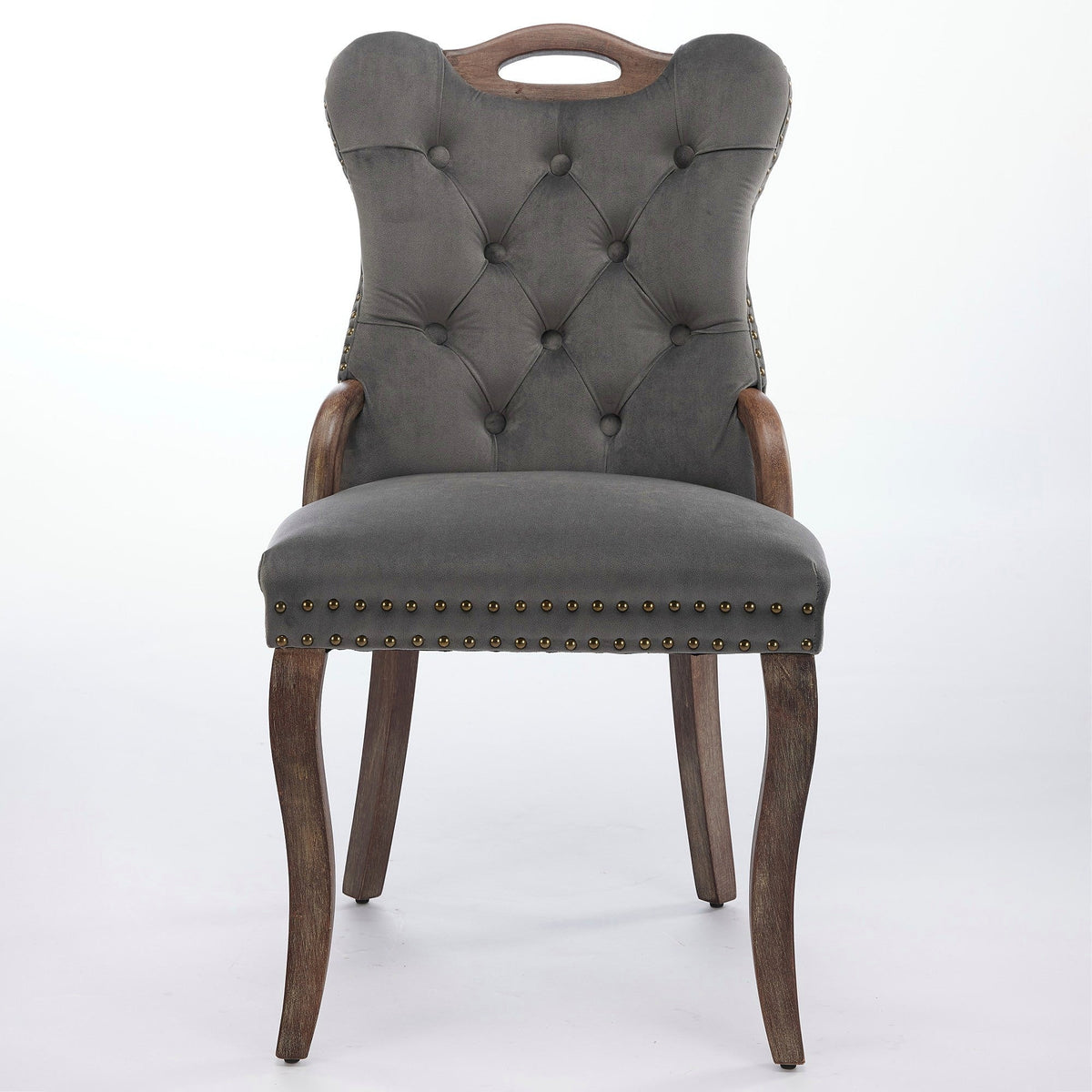 Gray velvet dining chair with a tufted back, wood handle, and curved wood legs