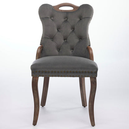 Gray velvet dining chair with a tufted back, wood handle, and curved wood legs