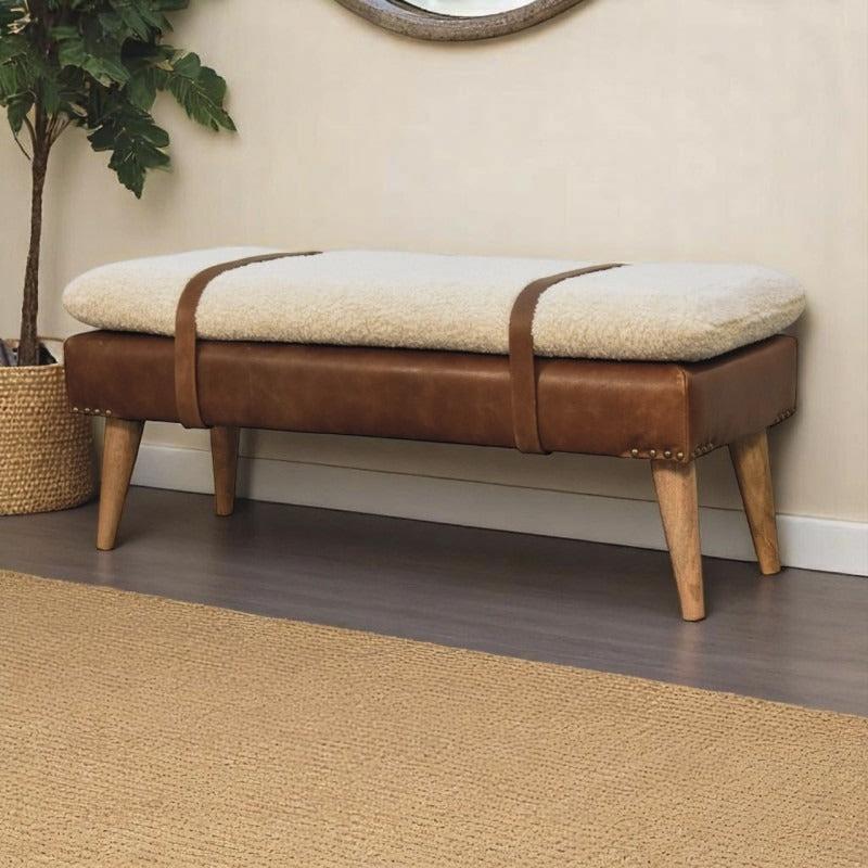 Cream boucle-style bench with brown straps and a leather-look base beside a houseplant