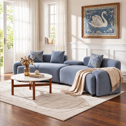 Blue-Grey Curved Sofa with Damask Pillows — blue-grey curved sofa in a sunlit room.