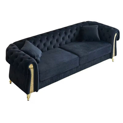 Angled view of the black velvet Chesterfield sofa and two toss pillows