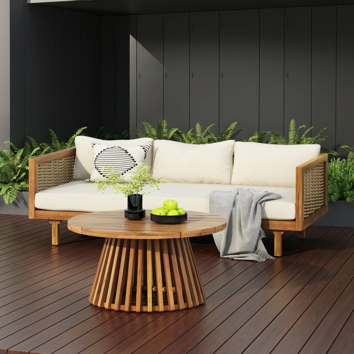 Patio sofa with beige cushions and a round slatted-base table on a dark deck