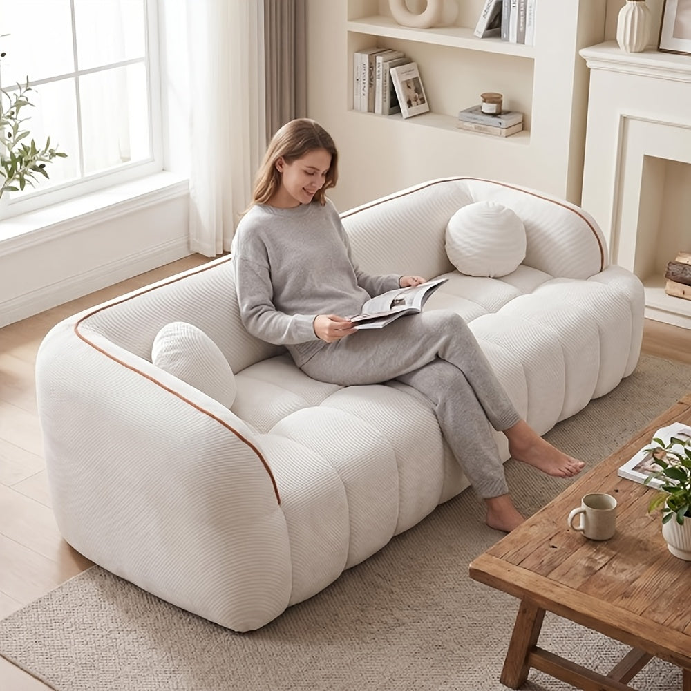 Channel-Tufted Corduroy Lounge Sofa — white sofa shown with seated reader.