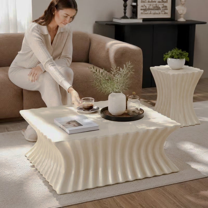 Woman reaching for a cup on a cream fluted coffee table with matching hourglass-shaped side table behind