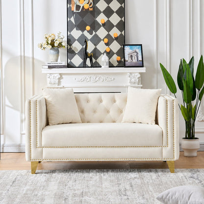 Beige velvet Chesterfield loveseat with gold-tone nailhead trim in a bright living room