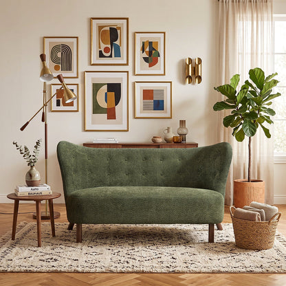 Olive green chenille loveseat with a curved back and wood legs beneath framed wall art.