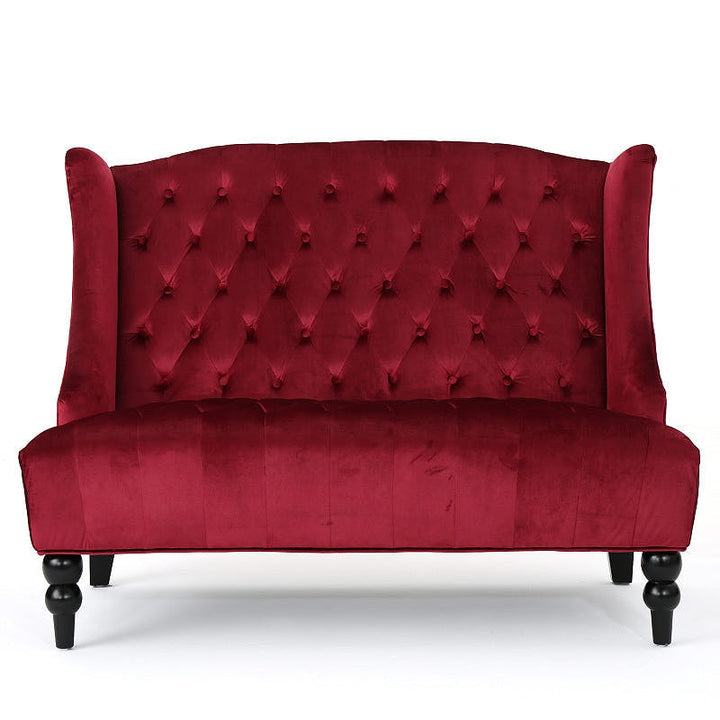 Front view of the wine red velvet loveseat with a high tufted back and turned front legs.