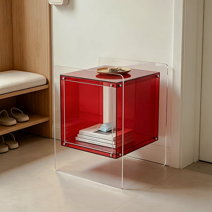 Red acrylic cube side table on clear supports beside a chair