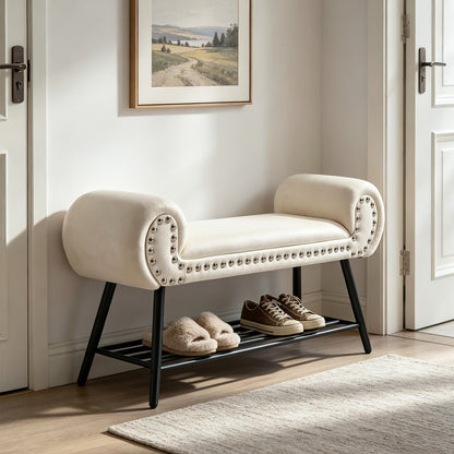Cream rolled arm upholstered shoe bench with a black metal rack and silver tone nailheads