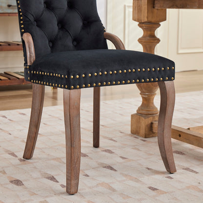 Black velvet dining chair with a tufted back, wood handle, and curved wood legs