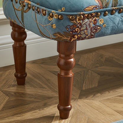 Close-up of floral upholstery nailhead trim and turned leg