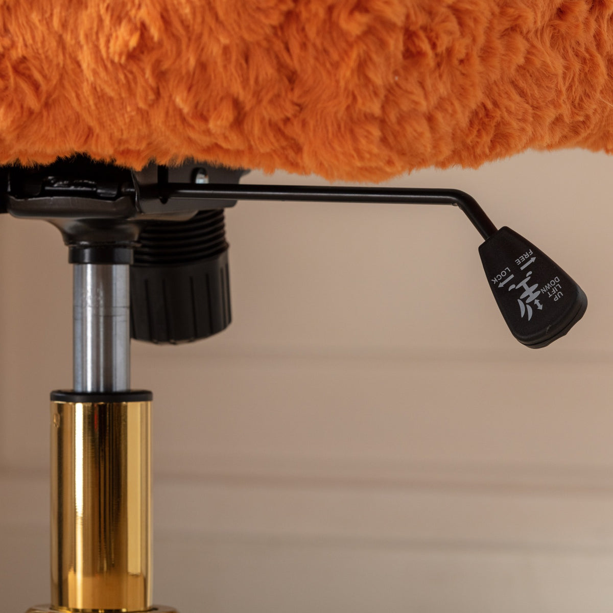 Close-up of the orange chair's adjustment lever and swivel column