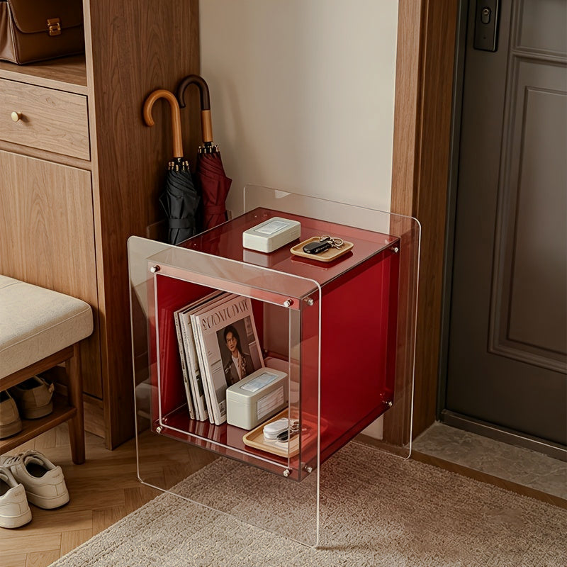 Red acrylic storage side table holding magazines near an entryway