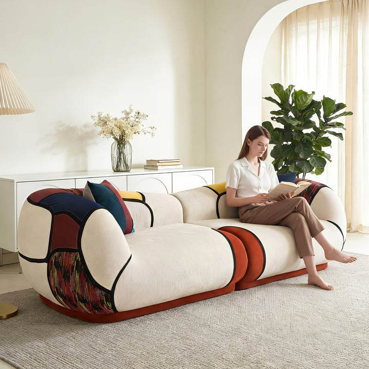 Curved colorblock sofa shown with a seated person to illustrate its scale.