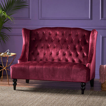 Wine red velvet wingback loveseat styled against a purple paneled wall.
