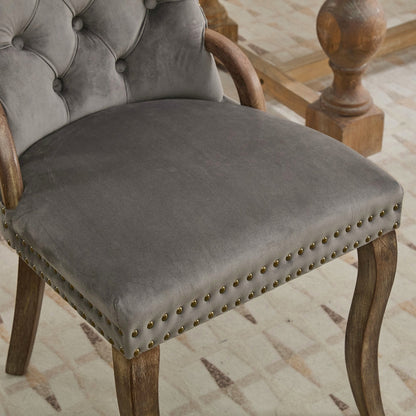 Gray velvet dining chair with a tufted back, wood handle, and curved wood legs