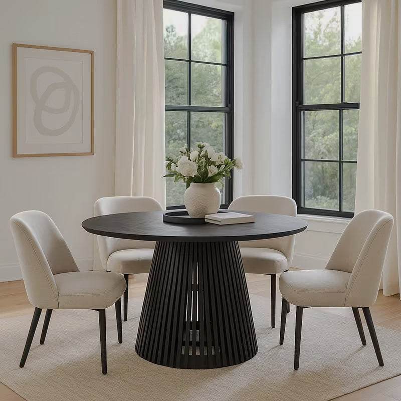Round black dining table with a flared slatted base and cream chairs