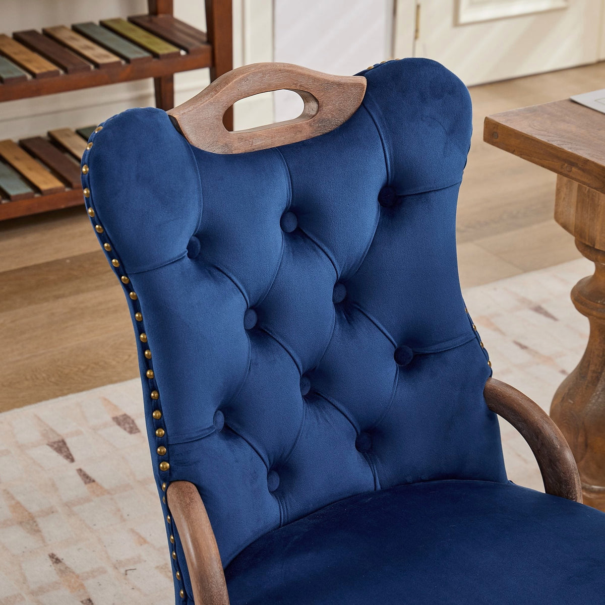 Blue velvet dining chair with a tufted back, wood handle, and curved wood legs