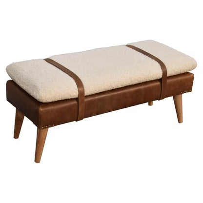 Angled view of rounded cream cushion and brown base on the strap-detail bench