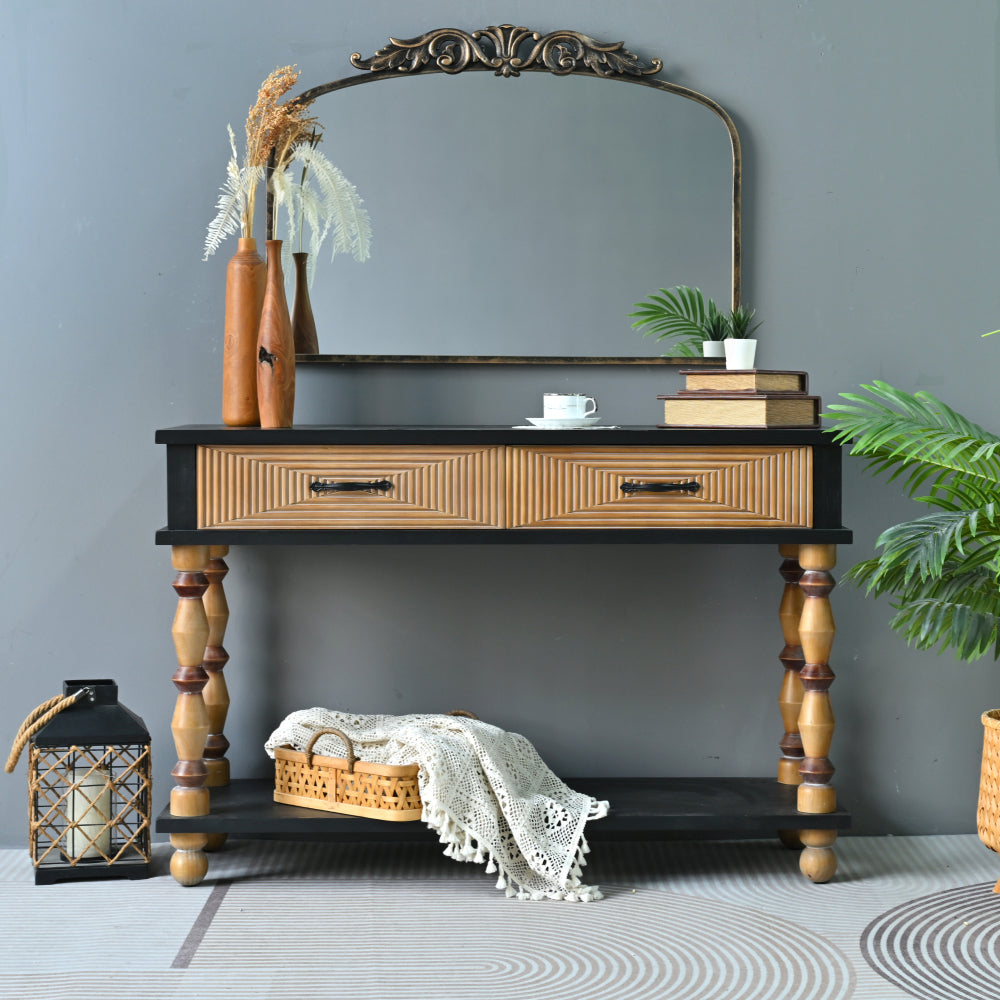 Black and natural brown console with two patterned drawers and turned legs against a blue-gray wall.