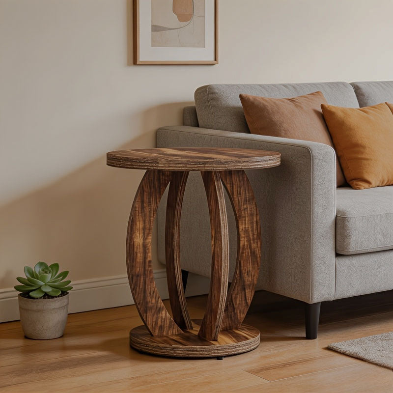 Walnut-finish round side table with curved open-ring supports beside a sofa.