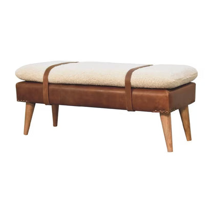 Three-quarter view of cream boucle-style bench with brown decorative straps and tapered legs
