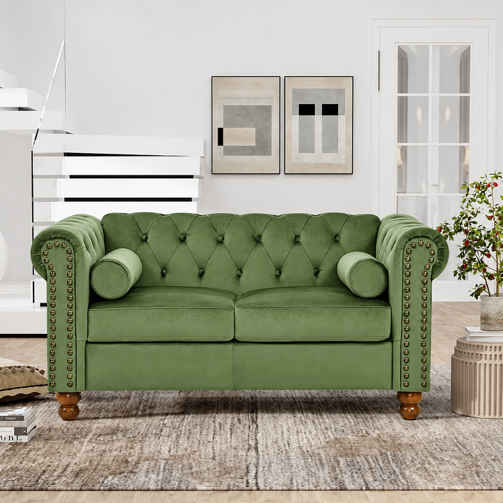Green velvet Chesterfield loveseat with rolled arms and nailhead trim in a bright living room