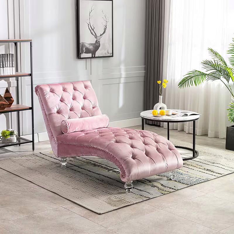 Pink velvet tufted chaise lounge with clear acrylic feet and a bolster pillow