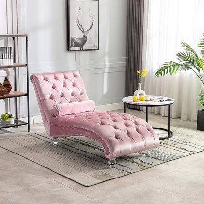 Pink velvet tufted chaise lounge with clear acrylic feet and a bolster pillow