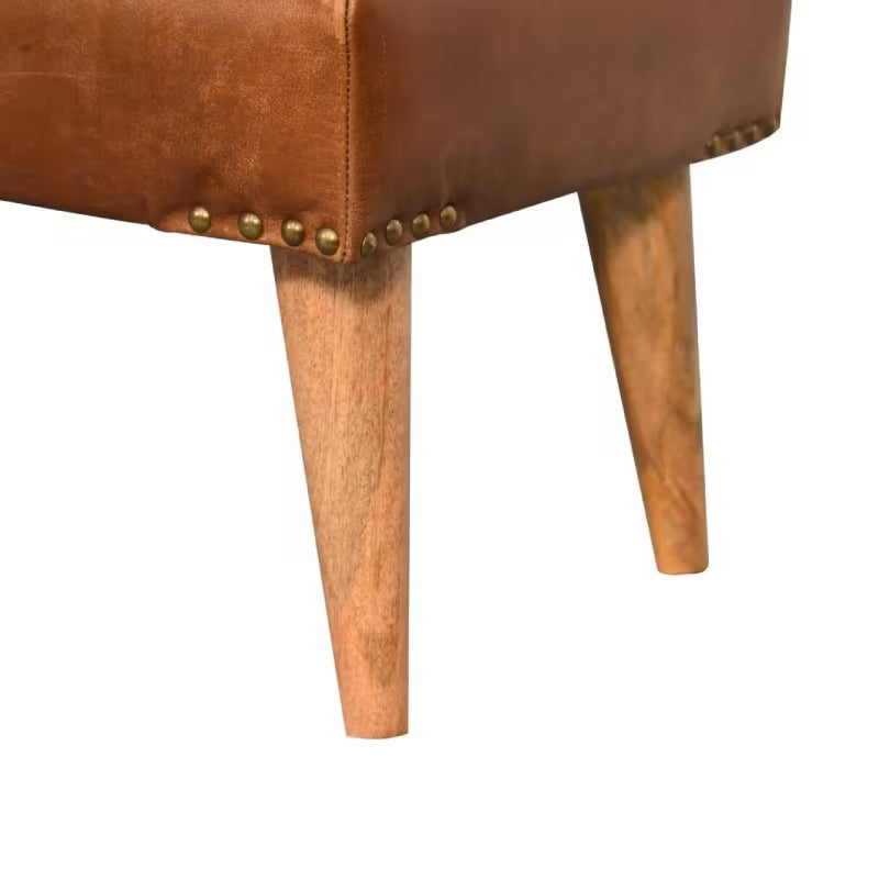 Close-up of tapered wood-tone bench leg and nailhead trim along the brown base